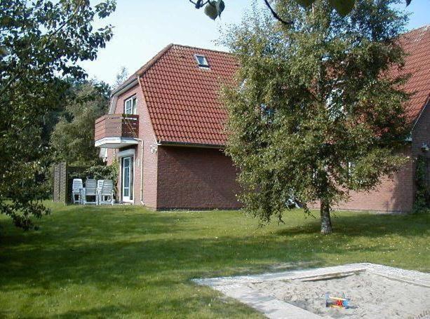 Haus-Boehler-Heide-Ferienwohnung-C2 في Süderhöft: منزل أمامه شجرة
