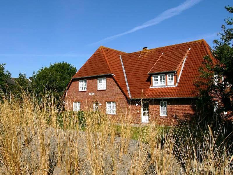 ein Haus mit rotem Dach am Strand in der Unterkunft Gästehaus Meene Menten - Wohnung MM 2 in Süderhöft