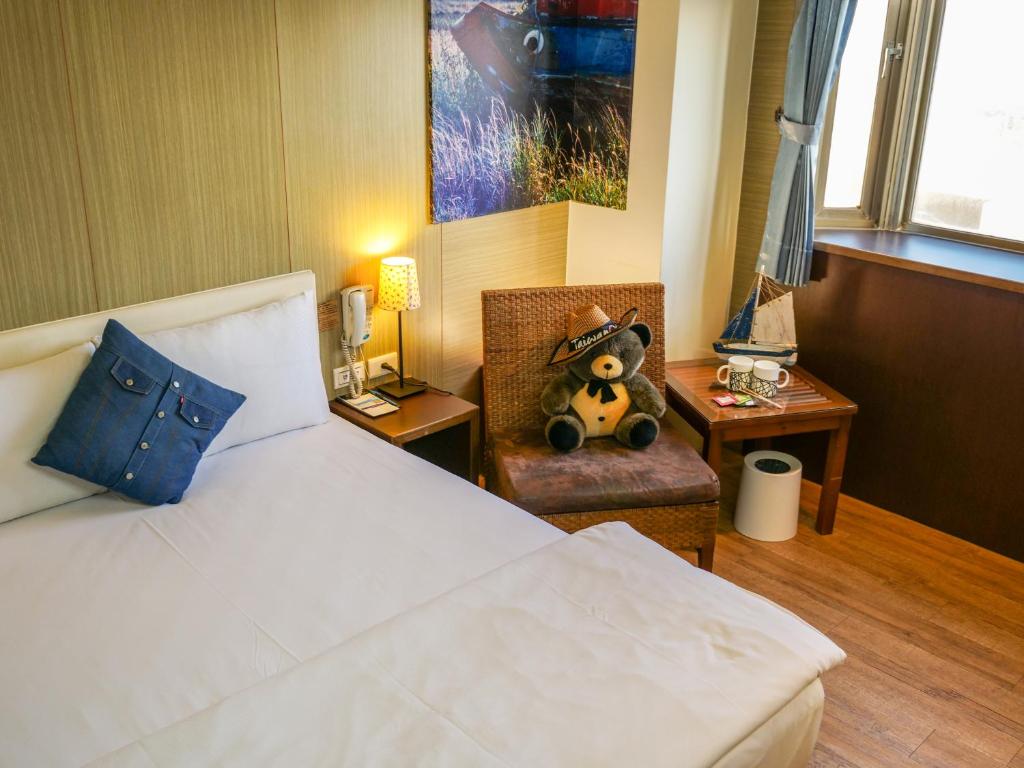 um quarto com uma cama com um urso de peluche numa cadeira em MF Hotel, penghu em Magong
