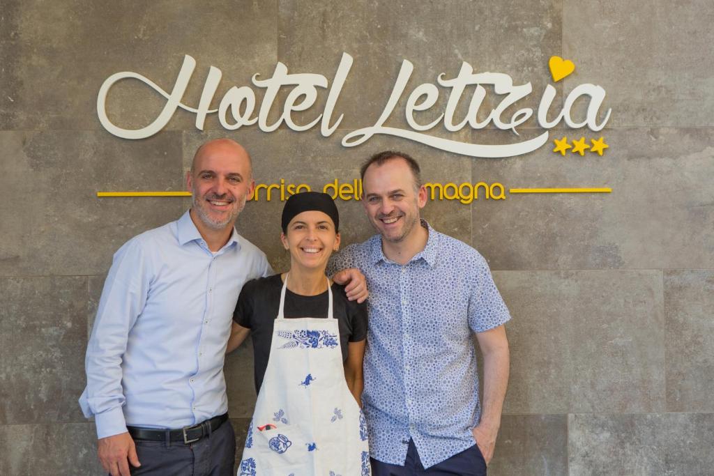 deux hommes et une femme debout devant un panneau dans l'établissement Hotel Letizia, à Bellaria-Igea Marina