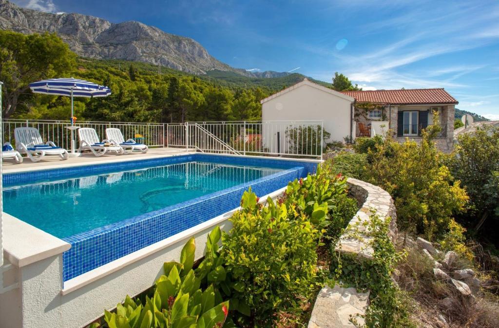 a swimming pool in a villa with a mountain in the background at Villa Marta in Tucepi, private pool in Tučepi