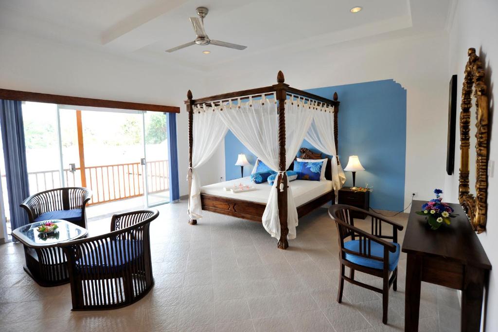 a bedroom with a canopy bed and a table and chairs at Aquarius Beach Hotel in Sanur