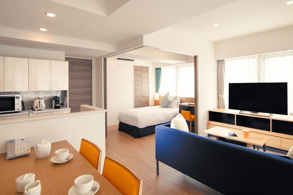 東京にあるオークウッドアパートメンツ西新宿のベッドとダイニングルームが備わるホテルルームです。
