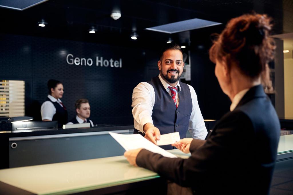 a man shaking hands with a woman at a desk at GenoHotel Forsbach in Rösrath