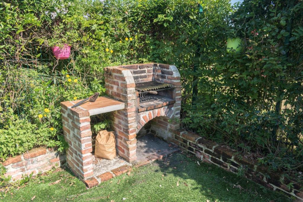 an outdoor brick oven in a garden next to a bush at Apartamentos Jardines de Llanes in Pancar