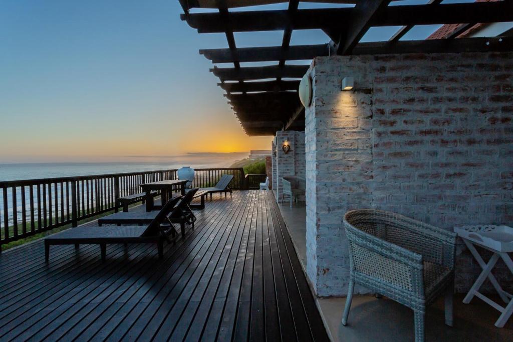a wooden deck with tables and chairs on the beach at Seeplaas Guesthouse in Groot Brak Rivier