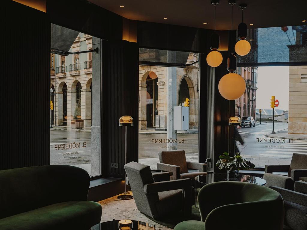 a room with chairs and windows with a view of a street at El Môderne Hotel in Gijón