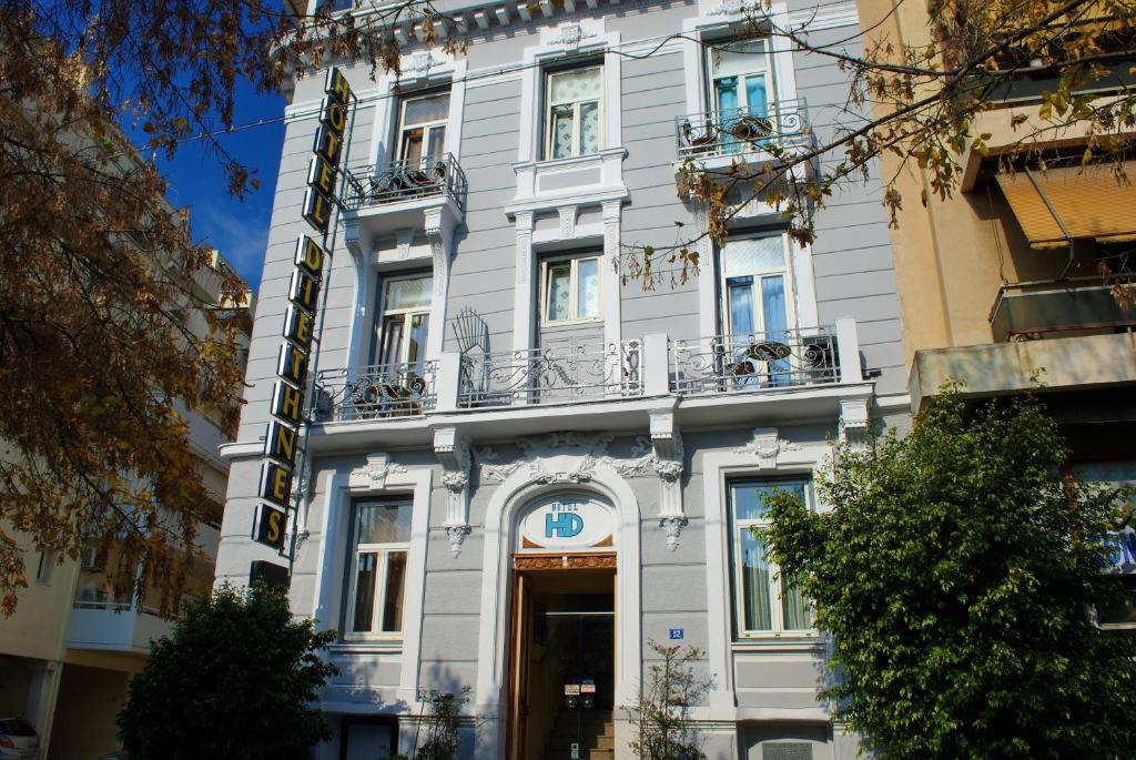 um grande edifício branco com uma porta e varanda em Diethnes Hotel em Atenas