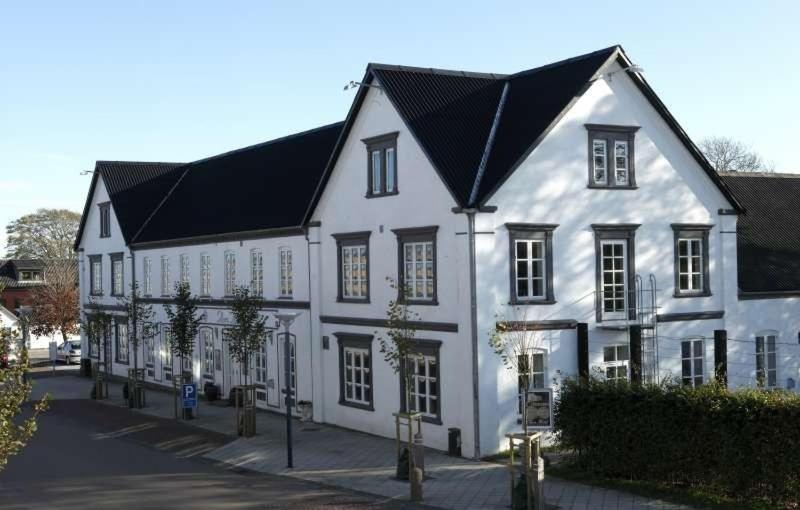 Aars Hotel في Års: مبنى ابيض كبير بسقف اسود