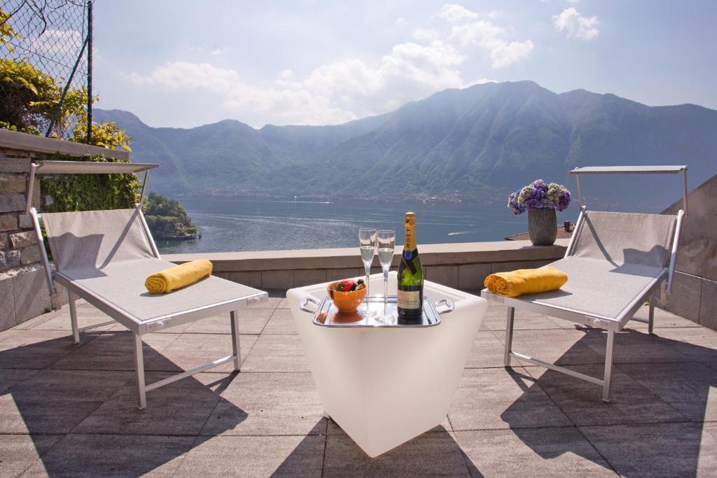 サーラ・コマチーナにあるApartment 5 - Overlooking Isola Comacina. Spacious living ideal for families of up to 10のテーブル、椅子2脚、ワイン1本付