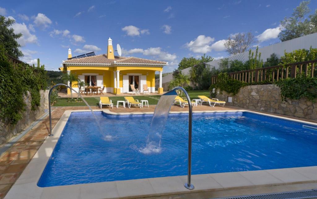 uma piscina com um escorrega de água em frente a uma casa em Villa Amarela em Boliqueime