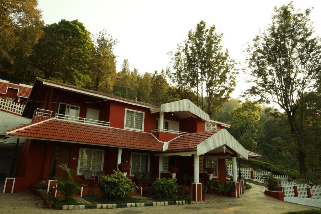a red house with trees in the background at Velu's Resort in Gūdalūr