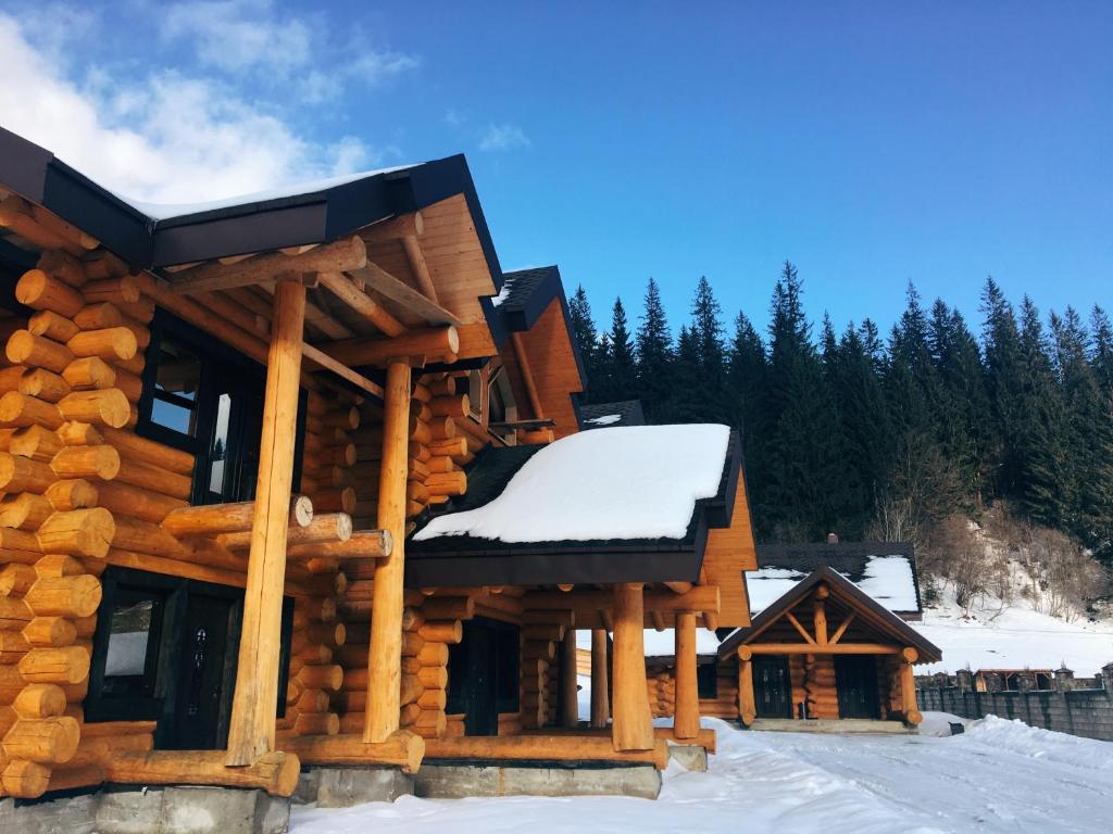 una cabaña de madera en la nieve con nieve en Зимова казка, en Tatariv