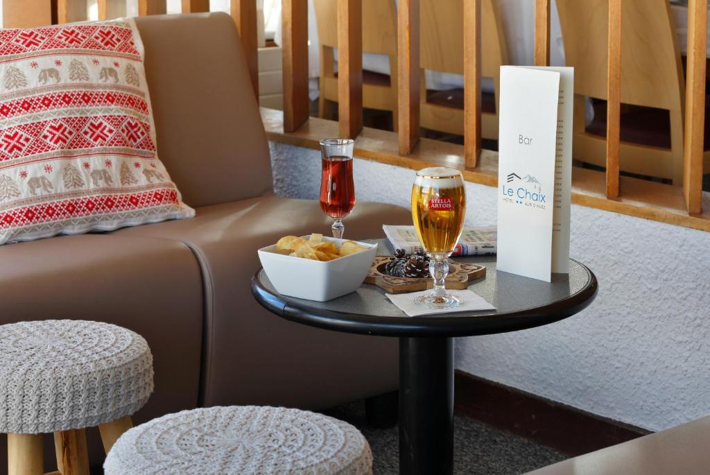 a table with two glasses of wine and a bowl of food at Hôtel Eliova Le Chaix in L'Alpe-d'Huez