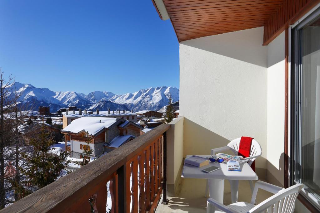 a balcony with a table and a view of the mountains at Hôtel Eliova Le Chaix in L'Alpe-d'Huez