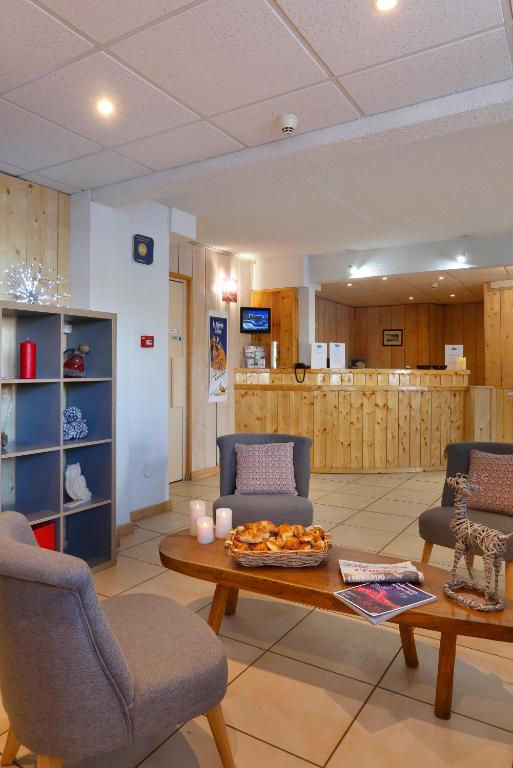 a living room with a coffee table and chairs at Hôtel Eliova Le Chaix in L'Alpe-d'Huez