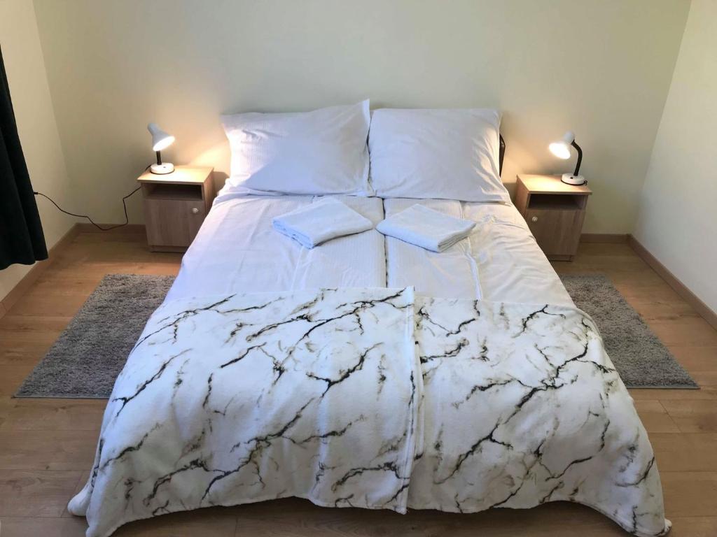 - un lit avec une couette blanche et 2 tables dans l'établissement Ella Apartman, à Debrecen