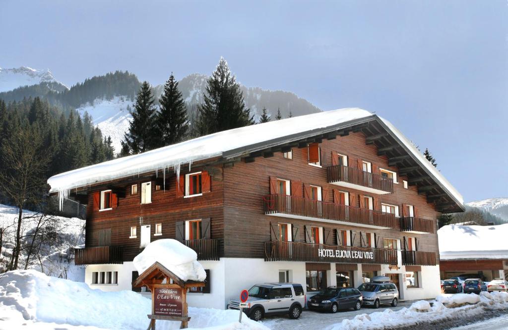 a large wooden building with snow on top of it at Hôtel Eliova l'Eau Vive in Châtel
