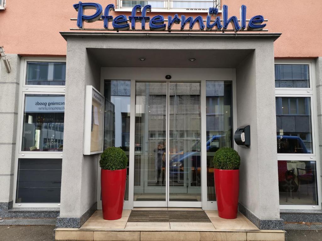 un magasin avec deux vases rouges devant une porte dans l'établissement Hotel-Restaurant Pfeffermühle Balingen, à Balingen