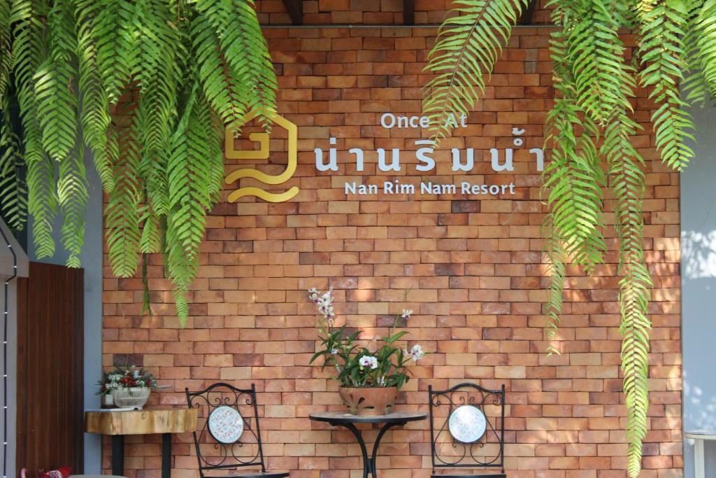 Una pared de ladrillo con un letrero que lee uno en el culto en Nan Rim Nam Resort, en Nan
