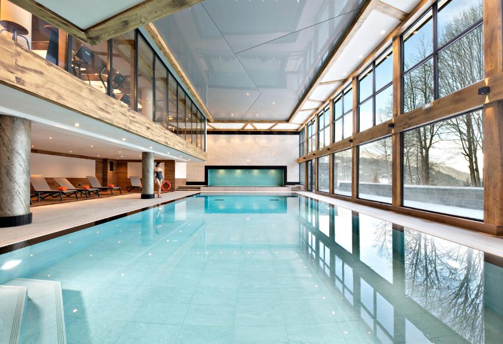 uma piscina interior com uma grande sala com janelas em Les Chalets Elena em Les Houches