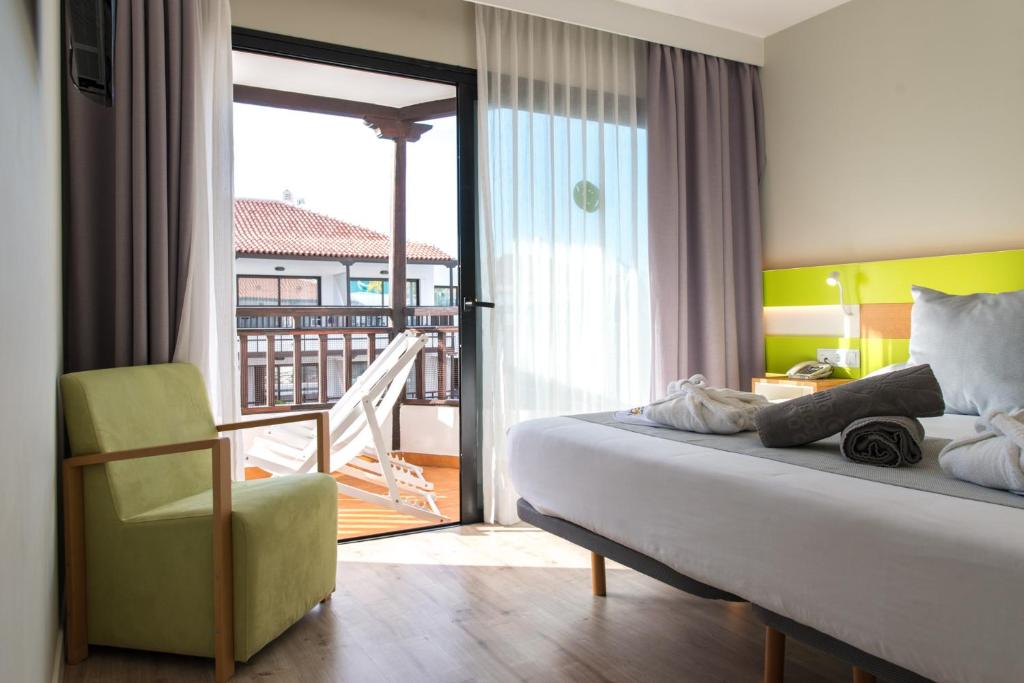 a bedroom with a bed and a chair and a balcony at Vanilla Garden Boutique Hotel - Adults Only in Playa de las Americas