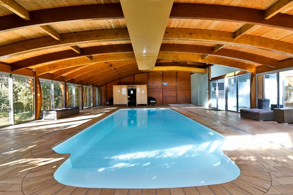 a swimming pool in a house with a wooden ceiling at Hotel SPA Plage St Jean in La Ciotat