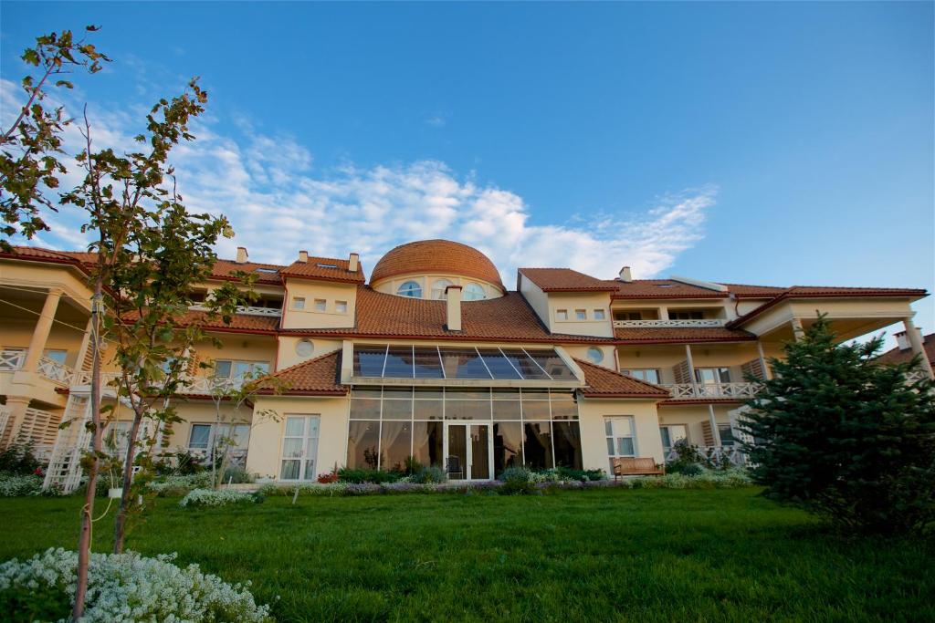 une grande maison avec un toit sur une pelouse verdoyante dans l'établissement Hotel Alexandria, à Anapa