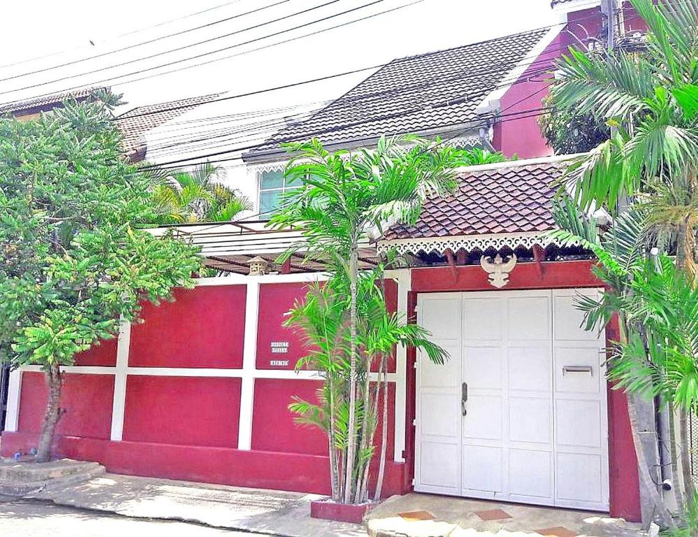 un garaje rojo y blanco con palmeras delante en 3BR Thai Style Home en Pattaya South
