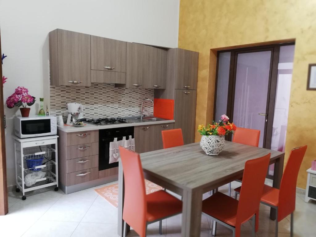 a kitchen with a wooden table and orange chairs at Abbronzatissima in Trapani