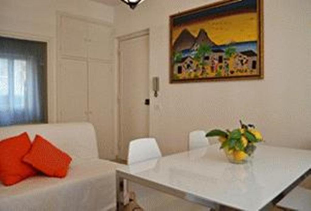 sala de estar con sofá blanco y almohadas de color naranja en Casa Elena, en Maiori