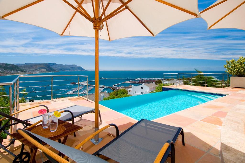 a villa with a swimming pool and an umbrella at Azure View Luxury Apartment in Simonʼs Town