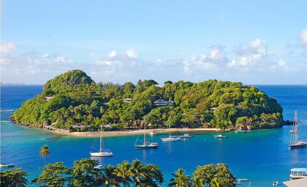 a small island with boats in the water at Young Island Resort in Kingstown