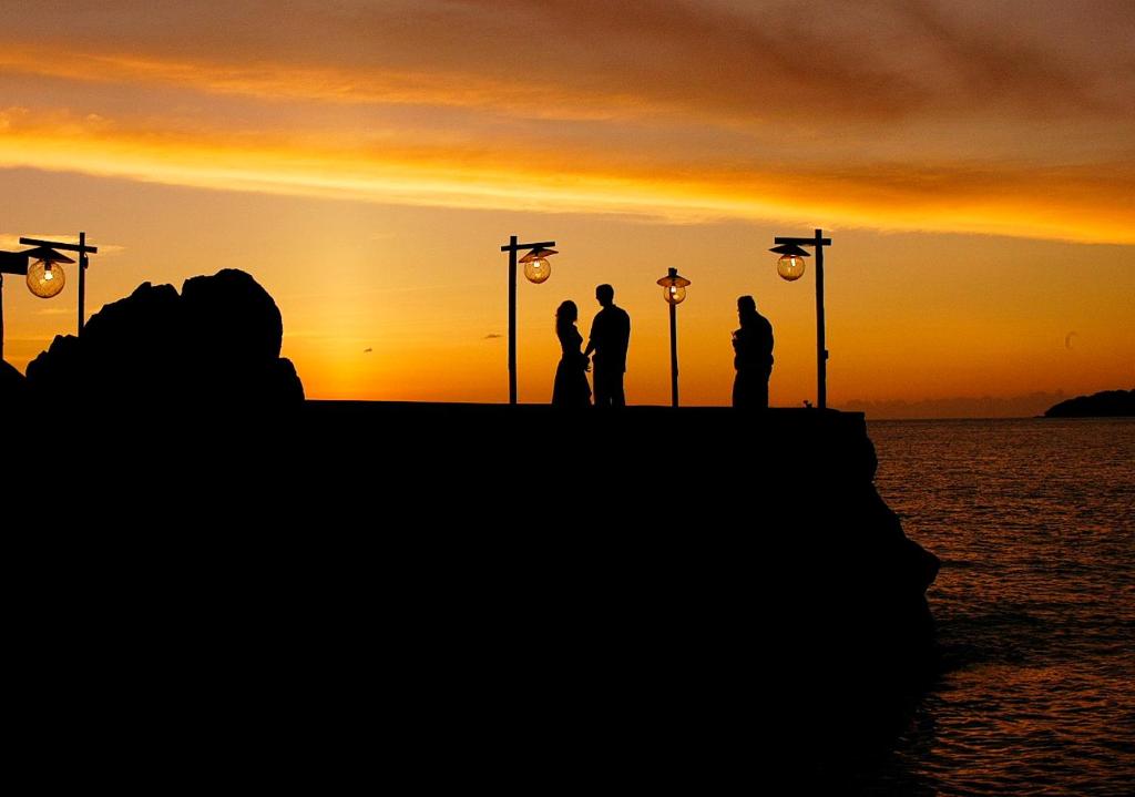 a group of people standing on a pier at sunset at Young Island Resort in Kingstown