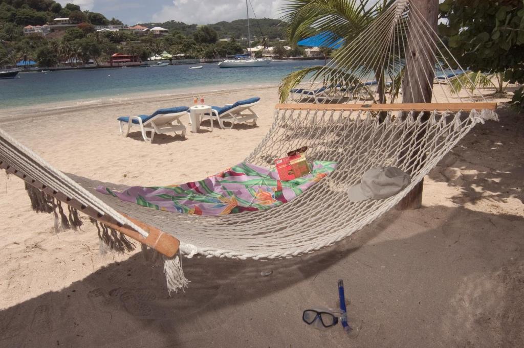 a hammock on a beach with a table and chairs at Young Island Resort in Kingstown