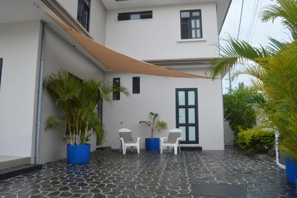 a courtyard of a house with chairs and palm trees at Sun Villa in Pereybere
