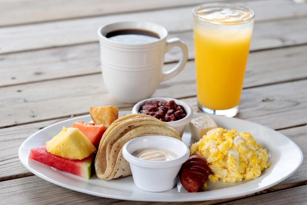 a plate of breakfast foods and a cup of orange juice at Splash Inn Dive Resort & Villas in West End