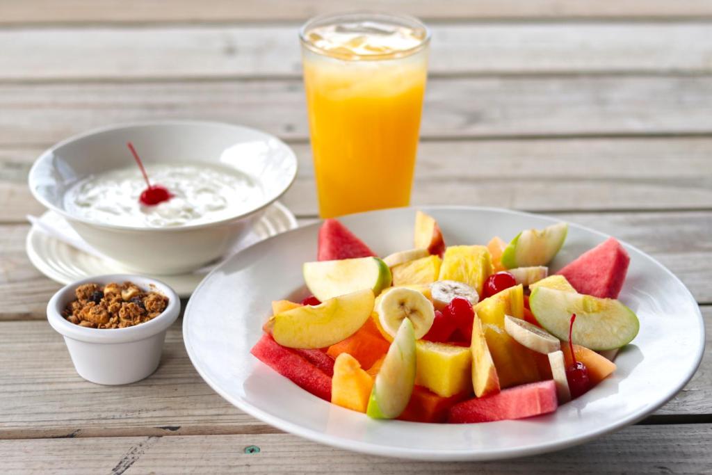 a plate of fruit on a table with a glass of orange juice at Splash Inn Dive Resort & Villas in West End