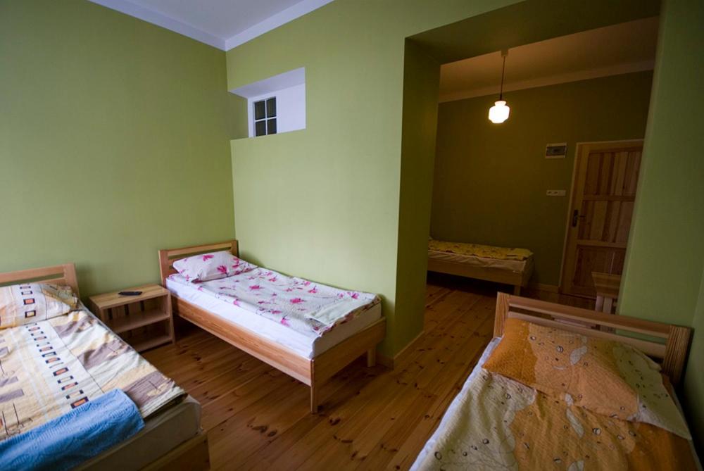 two beds in a room with green walls and wooden floors at Iskra in Augustów