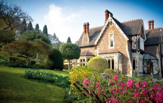 een groot bakstenen huis met bloemen in de tuin bij Cotford Hotel in Great Malvern