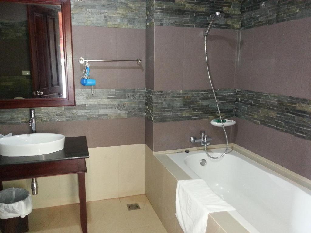 a bathroom with a bath tub and a sink at Pon Arena Hotel in Muang Không