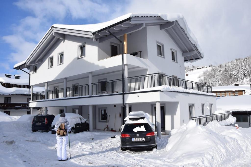 una persona parada frente a una casa en la nieve en Appartement Leogang, en Leogang