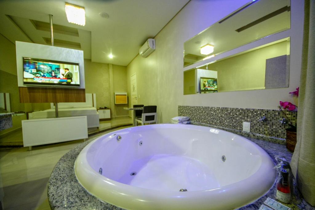 een grote badkamer met een groot bad en een televisie bij Motel Sedución (Adults only) in Cascavel