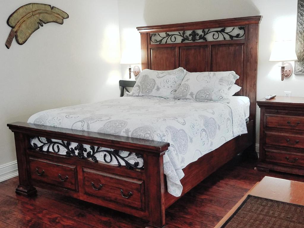 una camera con un grande letto con testiera in legno di Los Gatos Garden Inn Hotel a Los Gatos