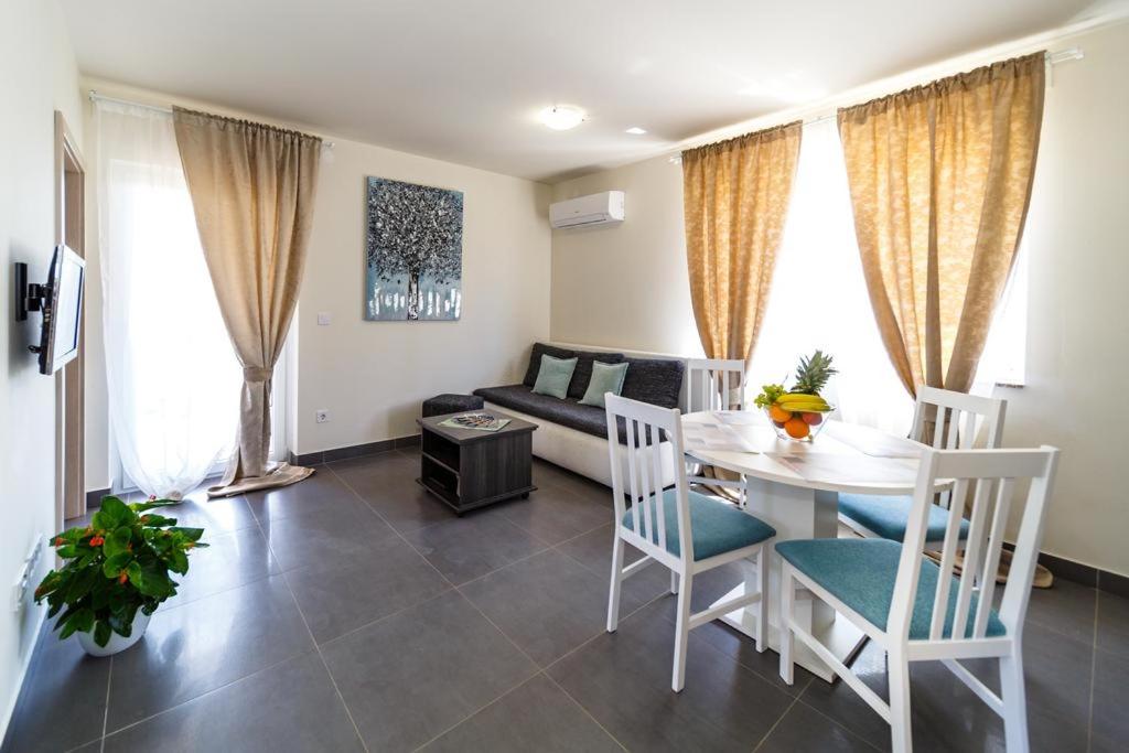 een woonkamer met een tafel en stoelen en een bank bij Apartments LeonDori in Krk