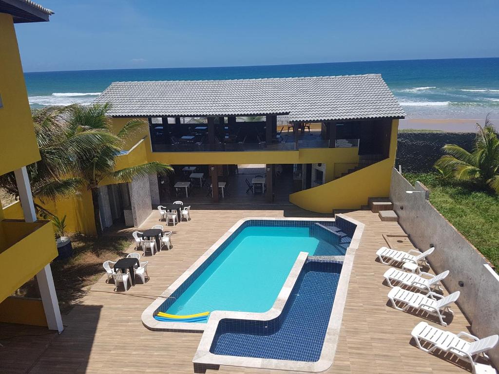 a resort with a swimming pool next to the beach at Pousada Águas do Piruí in Arembepe