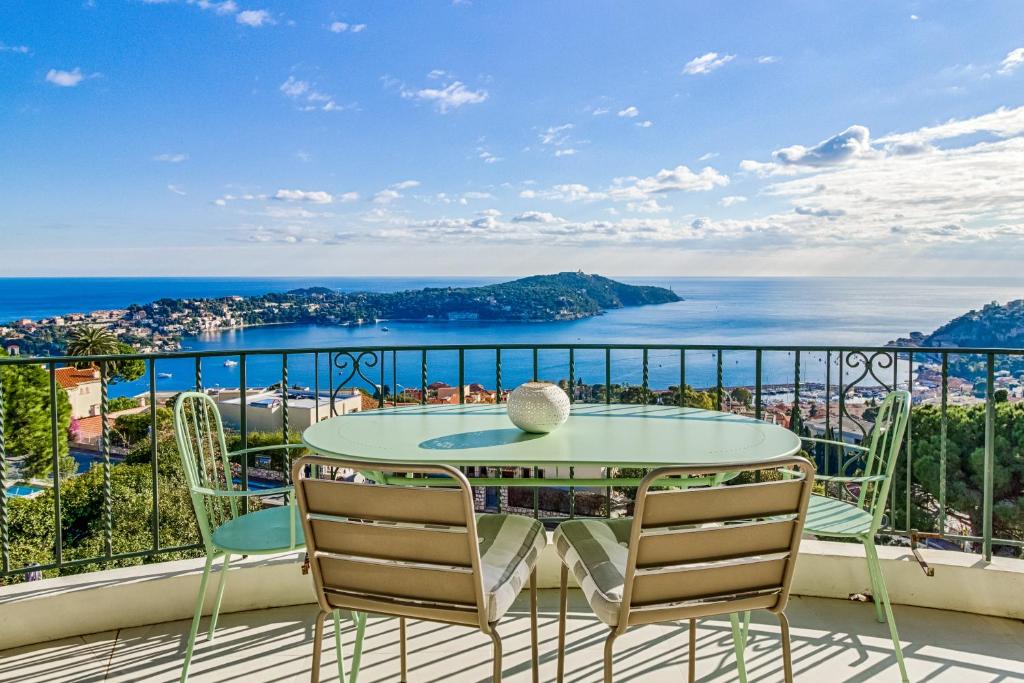 a table and chairs on a balcony with a view of the ocean at Luxurious Penthouse with panoramic view in Villefranche-sur-Mer