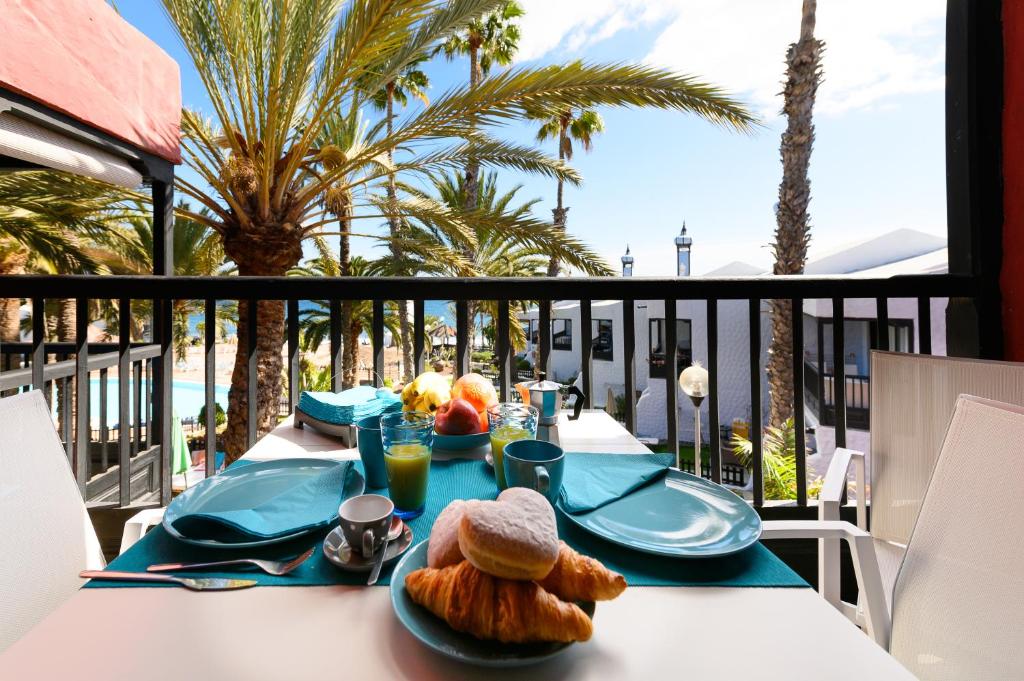 una mesa con comida en un balcón con palmeras en Luxury Bungalow Seaview - Sun Club Maspalomas, en San Bartolomé