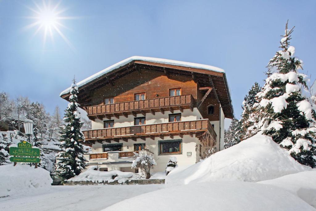 un bâtiment recouvert de neige avec un arbre recouvert de neige dans l'établissement Haus Scheibler, à Sankt Anton am Arlberg