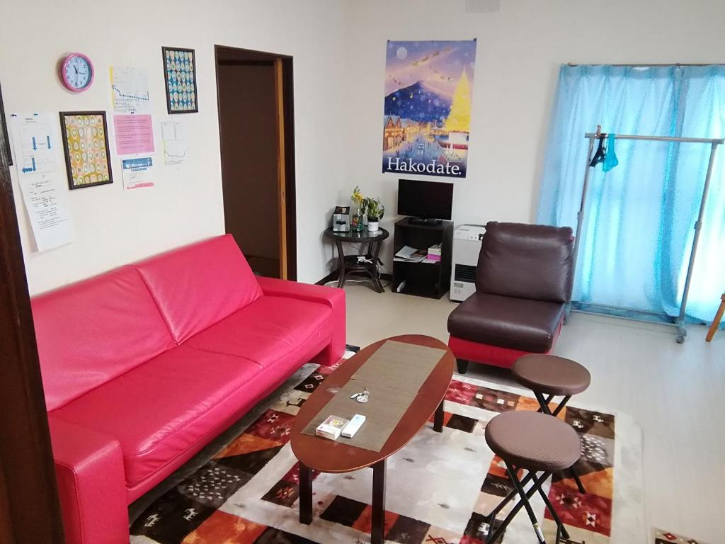 a living room with a red couch and a table at Corpo Marika A in Hakodate